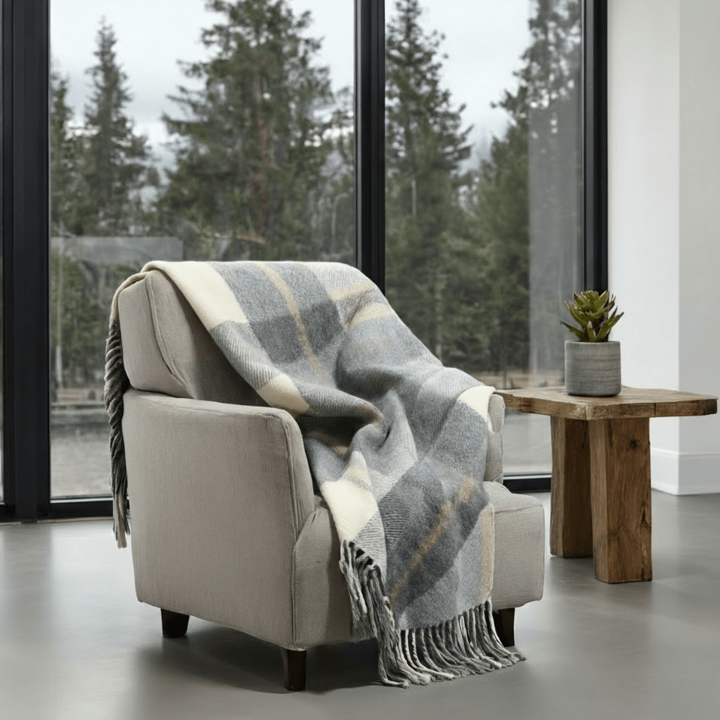 Kawartha Alpaca Blanket on armchair near window, blending warmth and durability with elegant plaid style in a cozy living room.