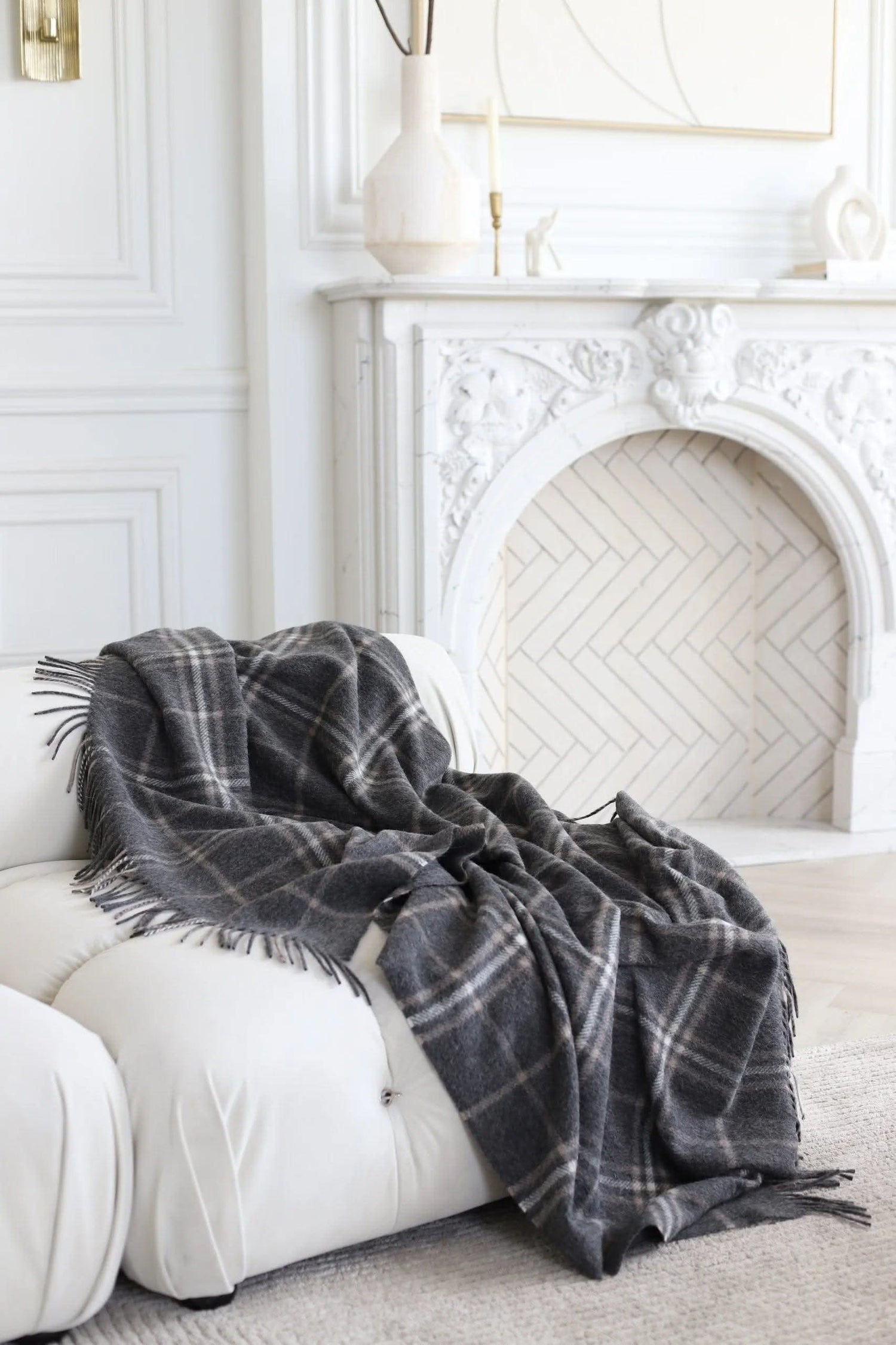 Kingston Alpaca Blanket draped over a white sofa in a luxury living room, highlighting its cozy wool texture and elegant plaid design.