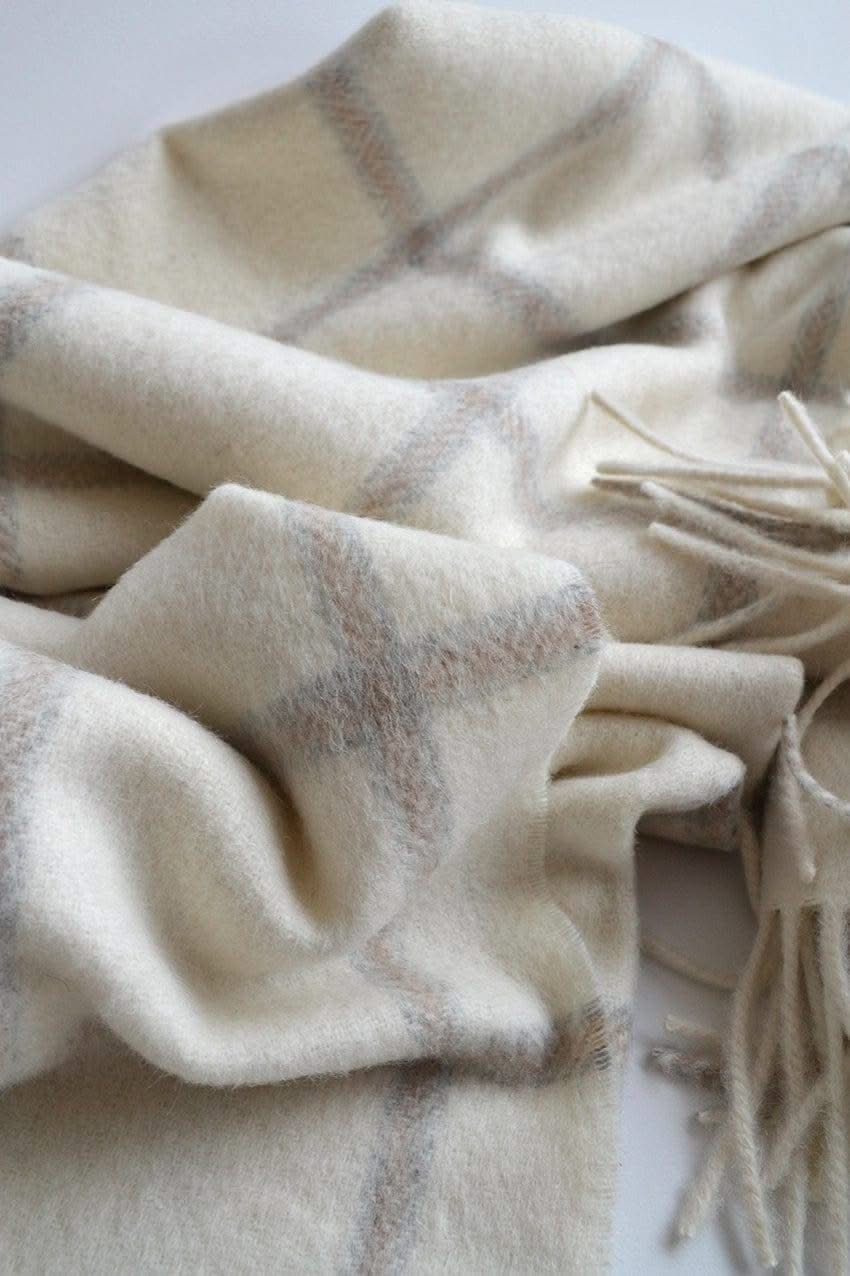 Close-up of the Picton Throw's soft alpaca-wool texture, highlighting its light grey check design and fringed edges.