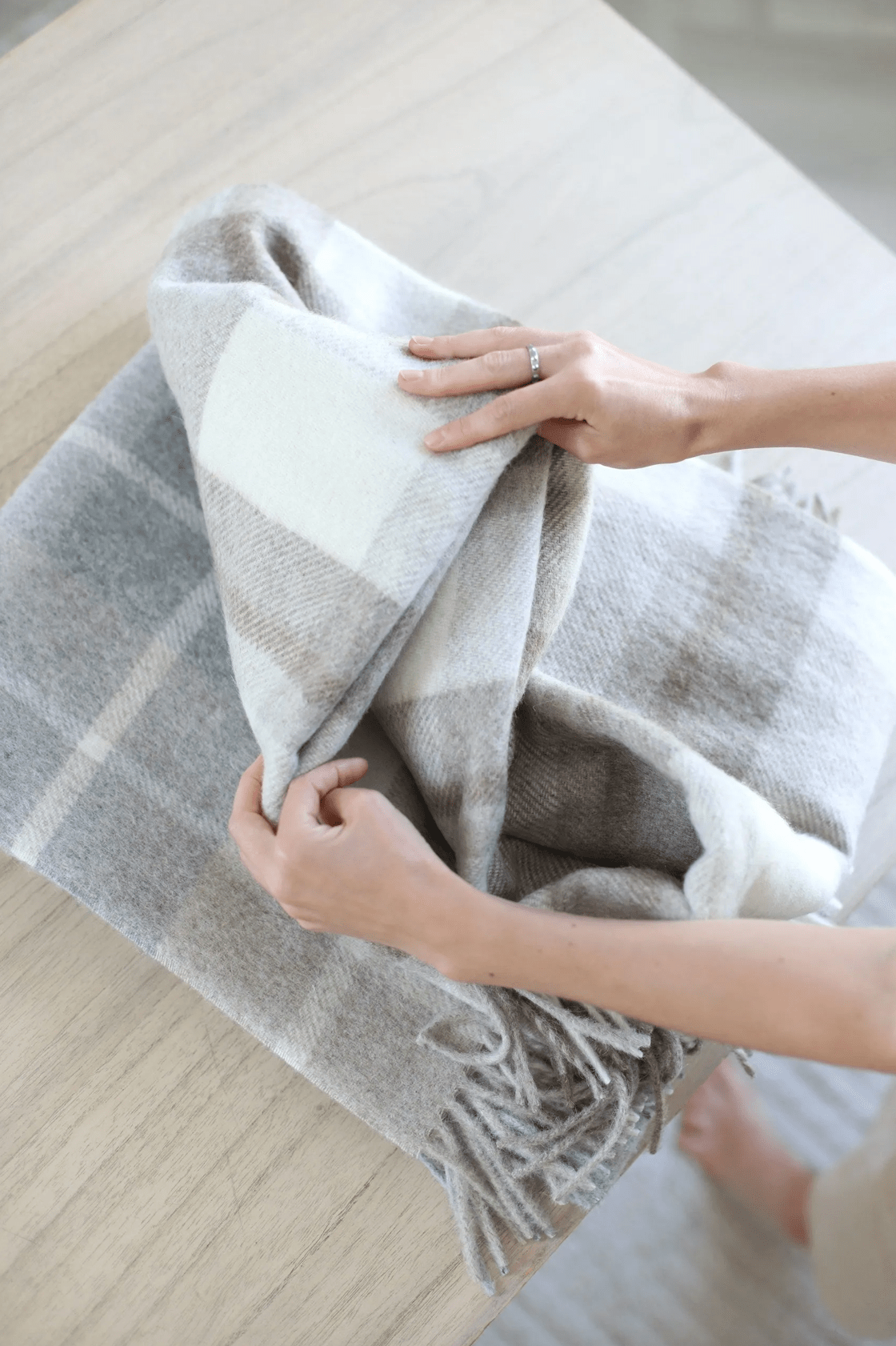 Hands folding the Kawartha Alpaca Blanket, emphasizing its soft, eco-friendly fabric and premium quality for cozy living spaces.