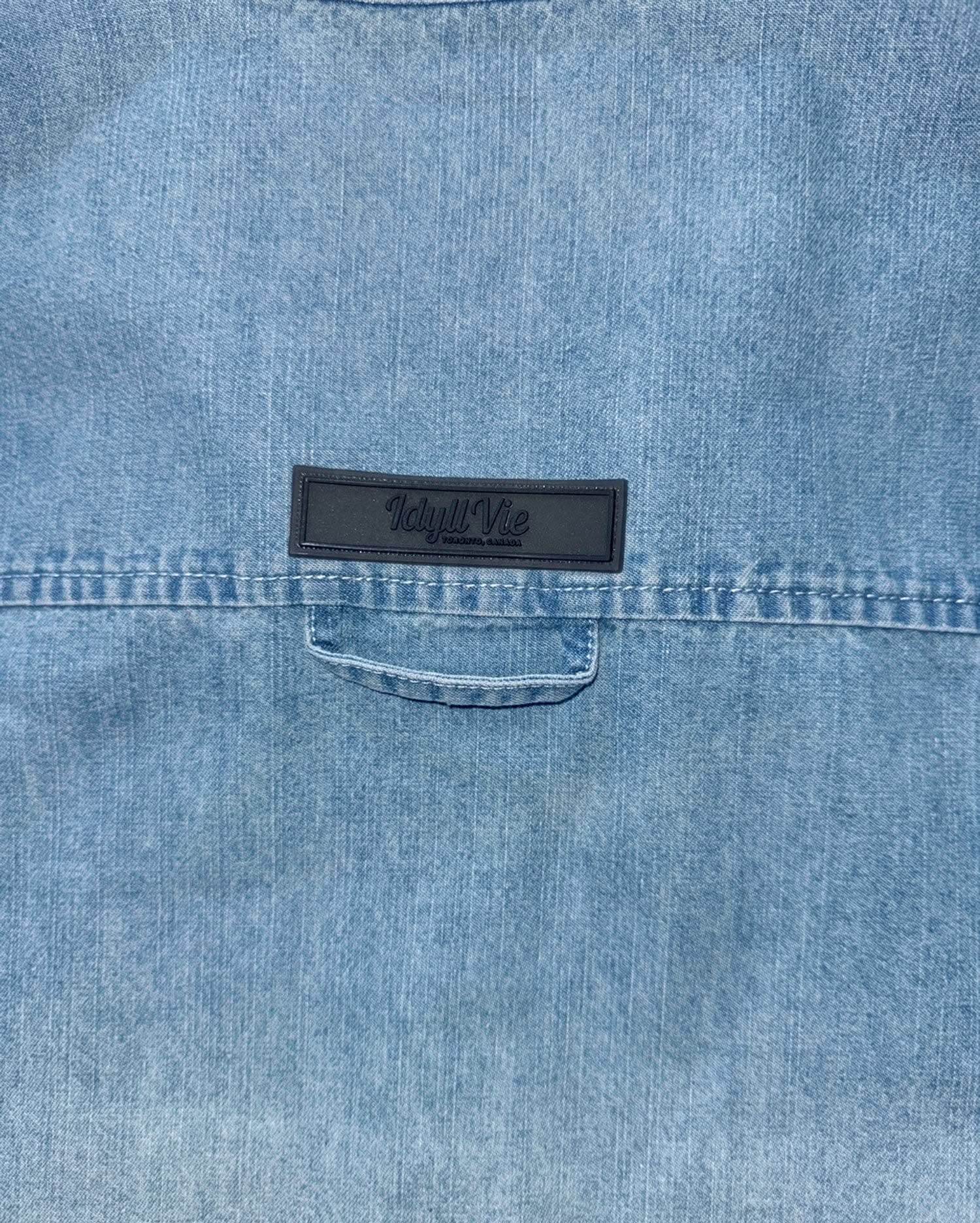 Detail of IdyllVie logo patch on the back yoke of the Oversized Denim Shirt, emphasizing brand identity and quality craftsmanship.