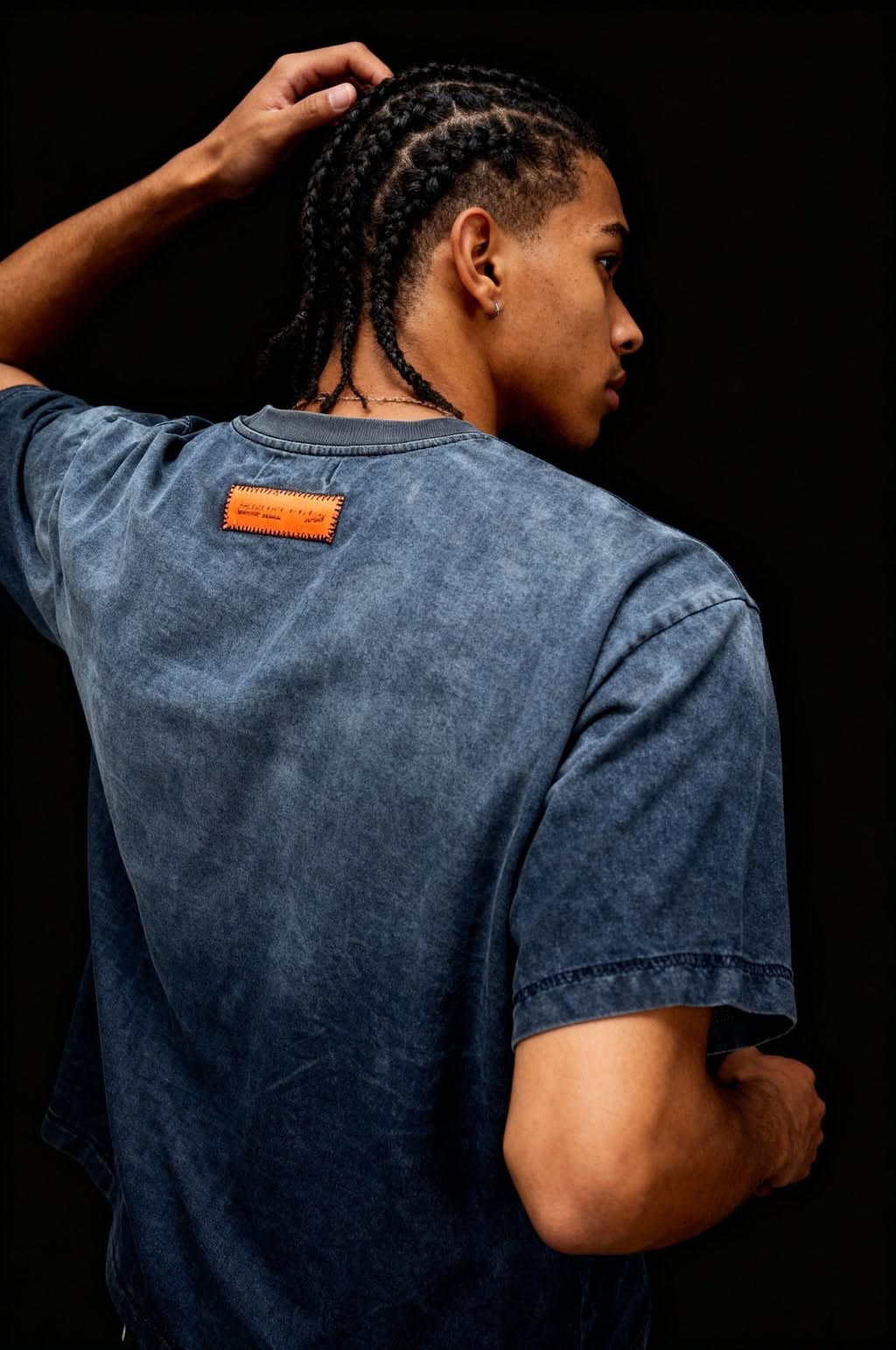Close-up side view of model wearing the 101 IdyllVie Studio Tee, emphasizing the textured cotton fabric and stitched orange label detail.