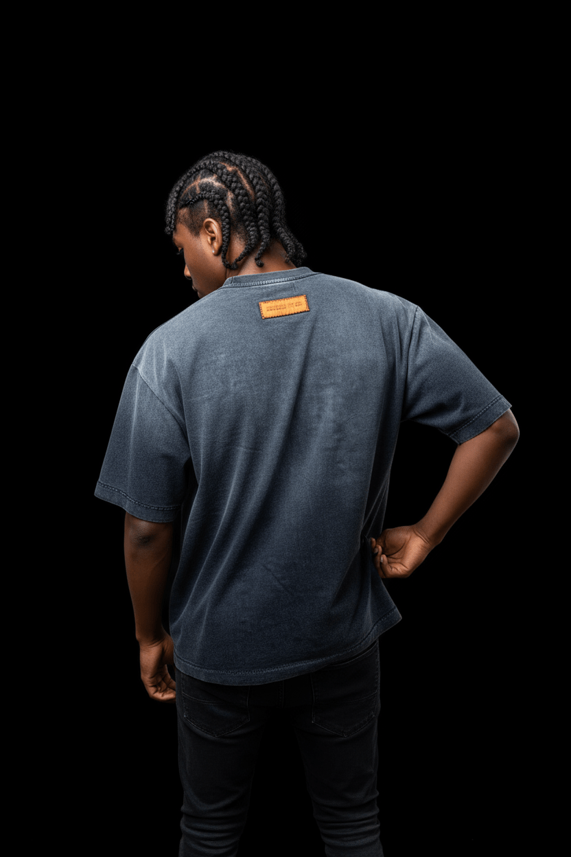 Rear view of model in the Studio Tee - Heavyweight Cotton T-Shirt, highlighting the orange label and washed black gradient design.