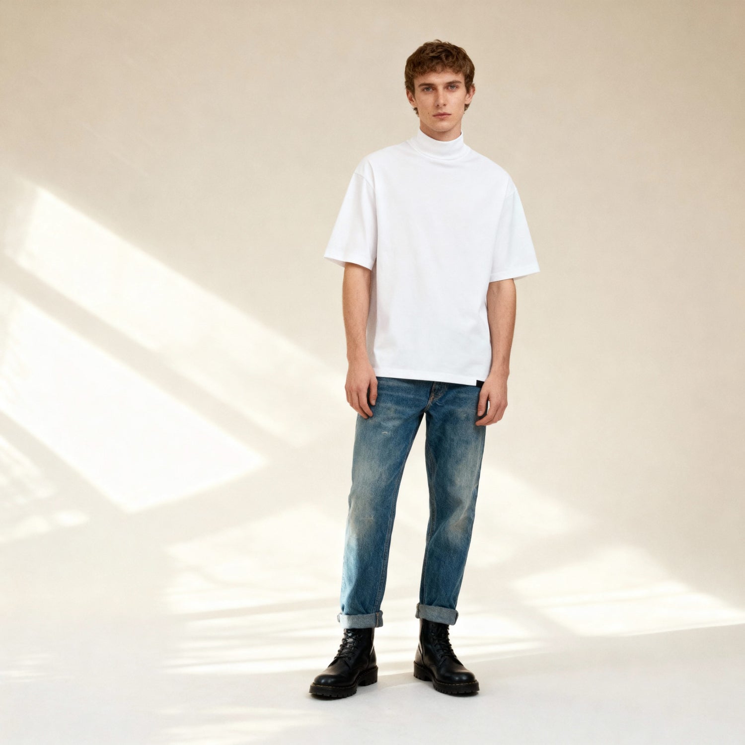 Model wearing the Mock Neck T-Shirt - White Cotton Essential paired with jeans and boots, showcasing a relaxed, effortless streetwear look.