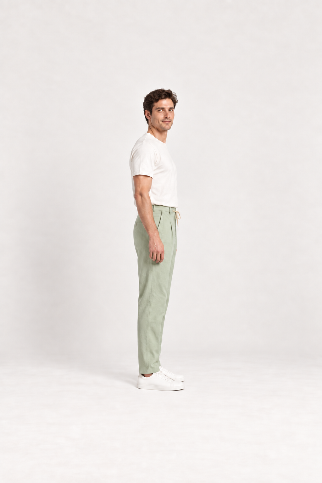 Green cotton pleated drawstring pants, side view on an adult model.