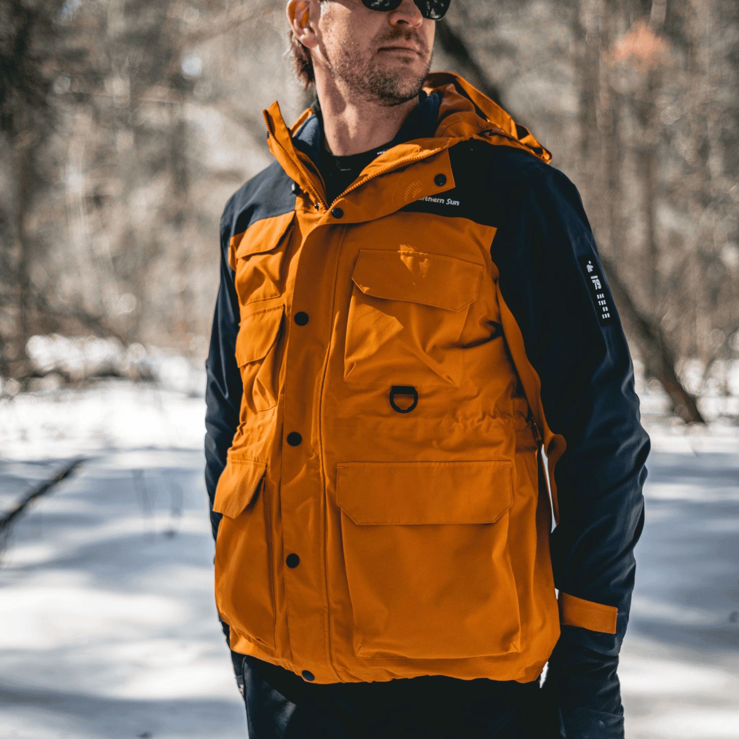 Man wearing Northern Sun 3-in-1 Waterproof Winter Parka in snowy forest, showcasing rugged outdoor use and weather resistance.