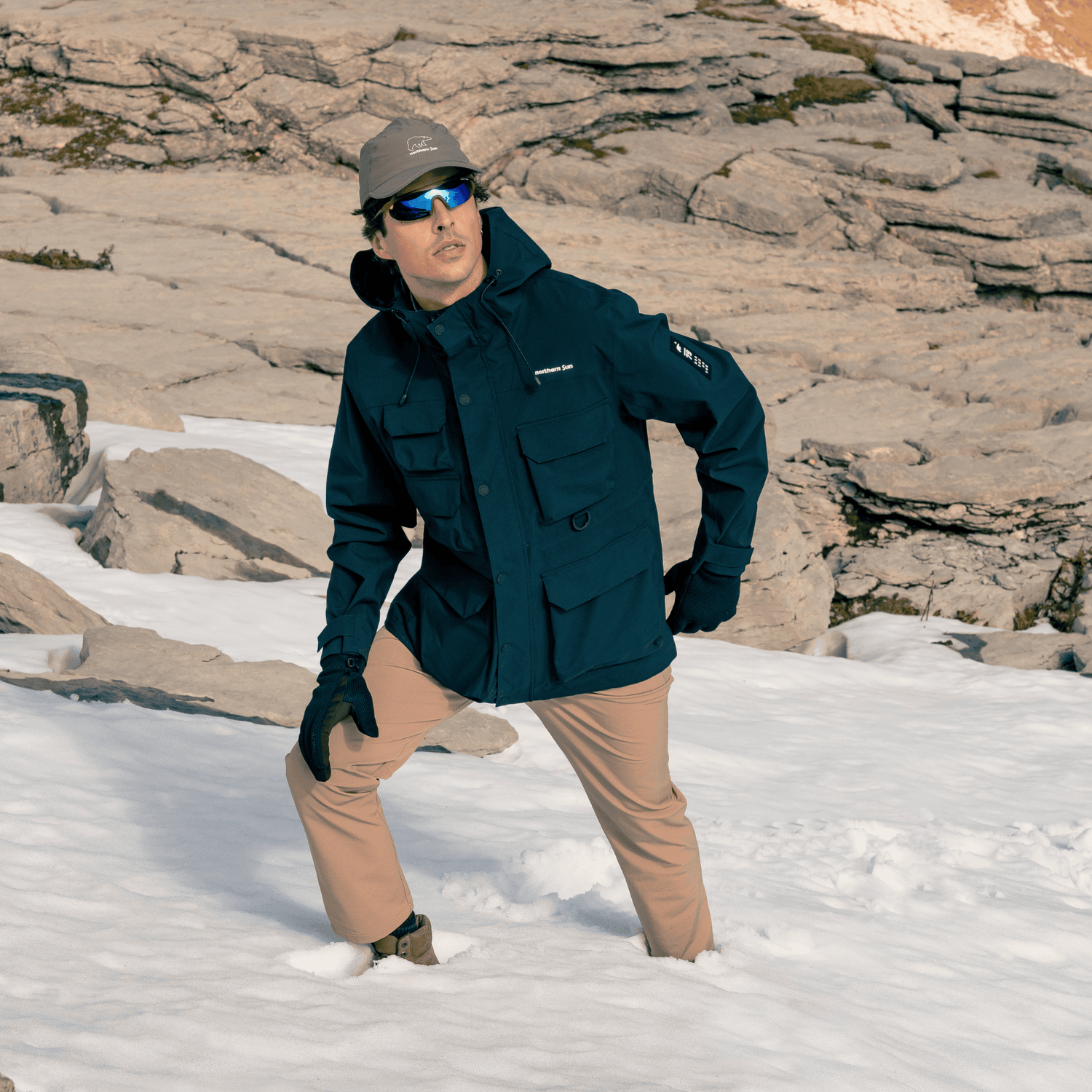 Man hiking in snow wearing navy Northern Sun 3-in-1 Waterproof Winter Parka, showing versatility in alpine conditions.
