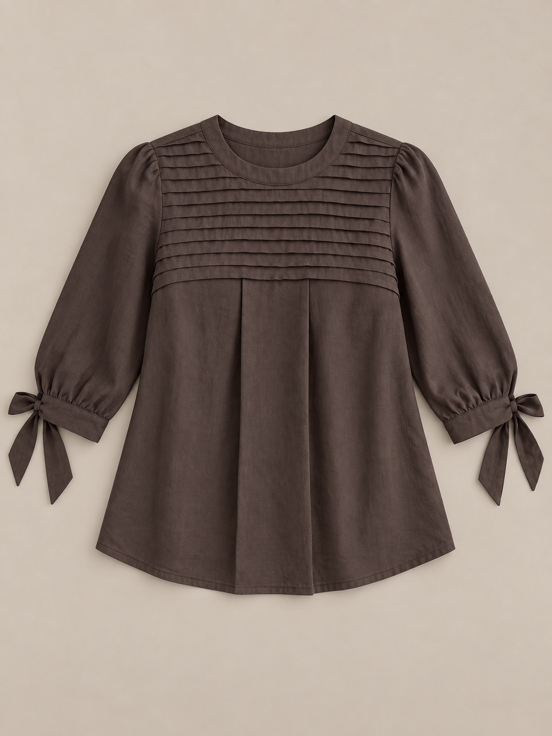 Brown blouse with pleated chest and three-quarter tie cuffs, flat lay front.