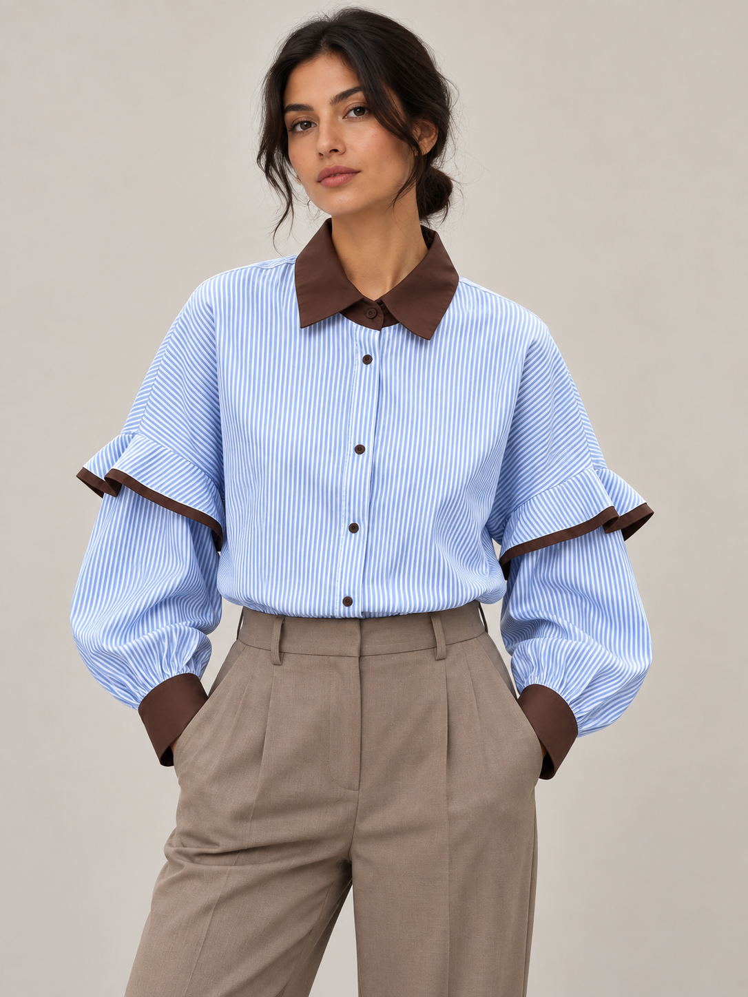 Blue and white striped shirt with brown collar and ruffled sleeve joins, front styling view tucked into trousers.