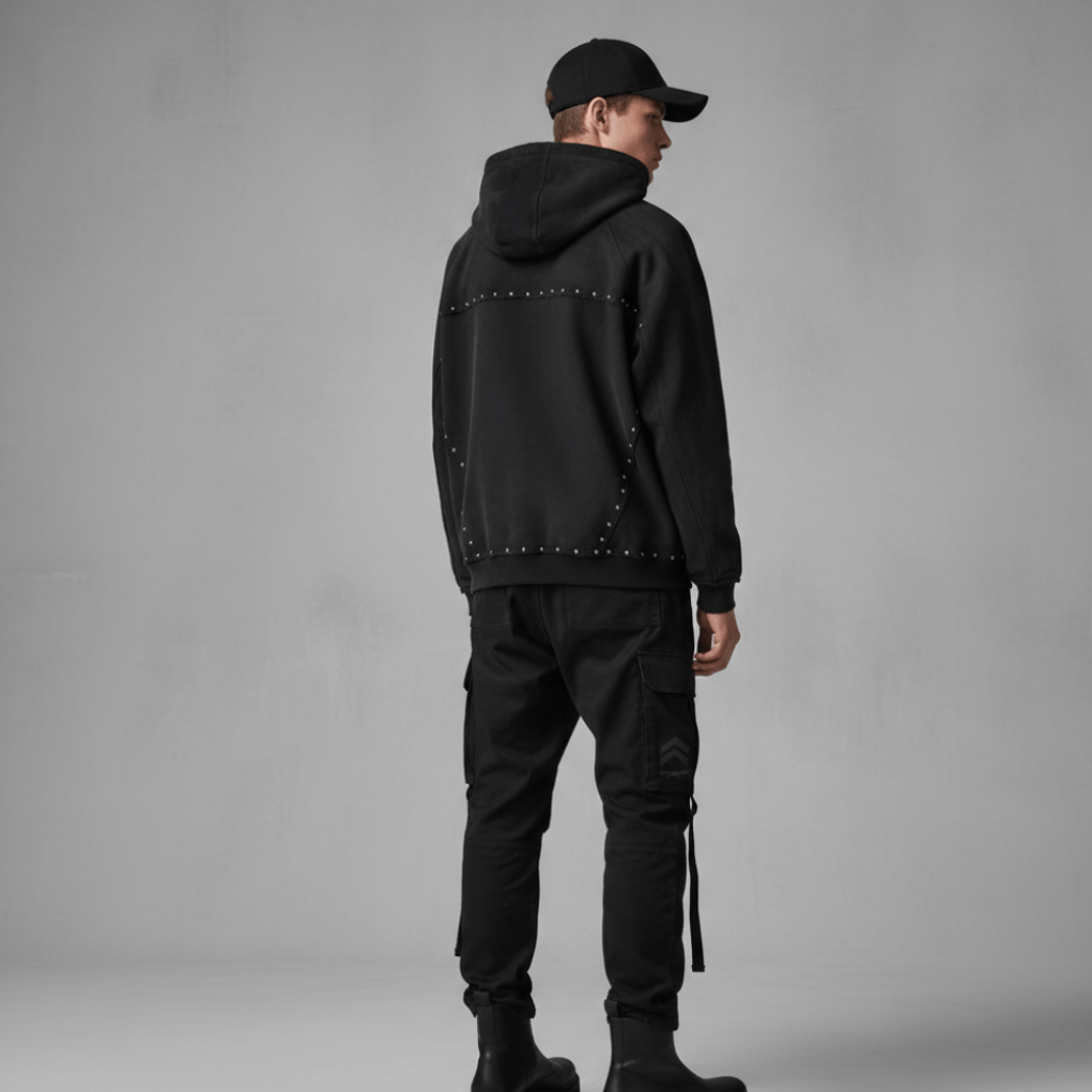 Back view of male model wearing black studded hoodie. Showcases unique stud pattern and relaxed fit in heavyweight cotton fabric.