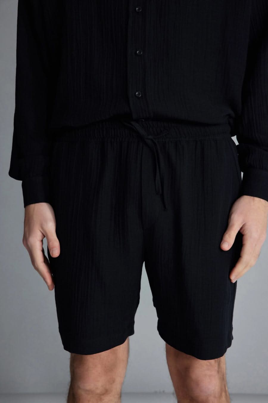 The Porterville Shorts in black 100% cotton muslin, lifestyle view showing drawstring waist, front pockets, cotton muslin texture