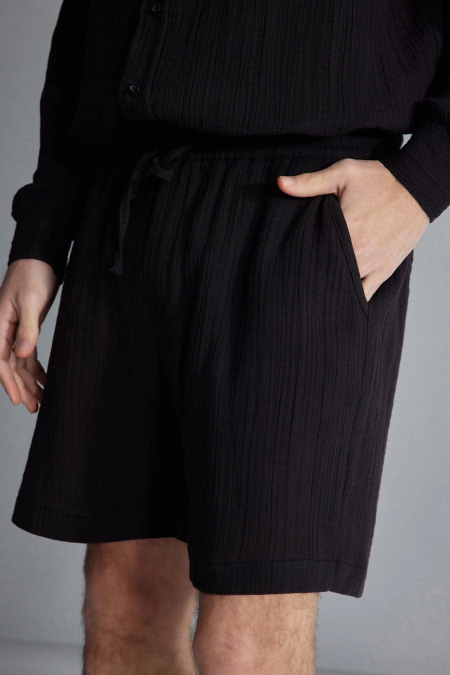 The Porterville Shorts in black 100% cotton muslin, lifestyle view showing drawstring waist, front pockets, cotton muslin texture