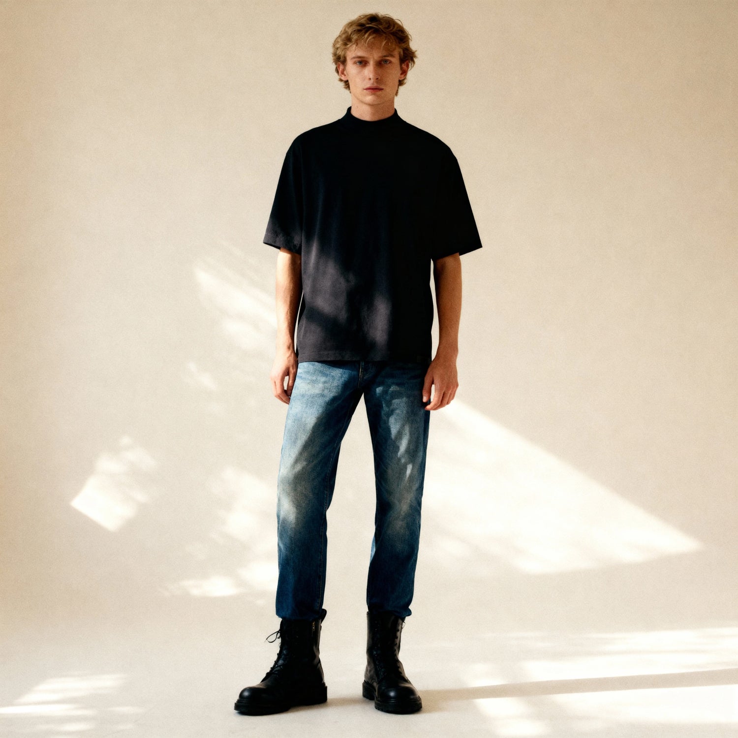 Model wearing the Black Mock Neck Cotton T-Shirt with jeans and boots, demonstrating its casual yet stylish appeal for men's clothing.