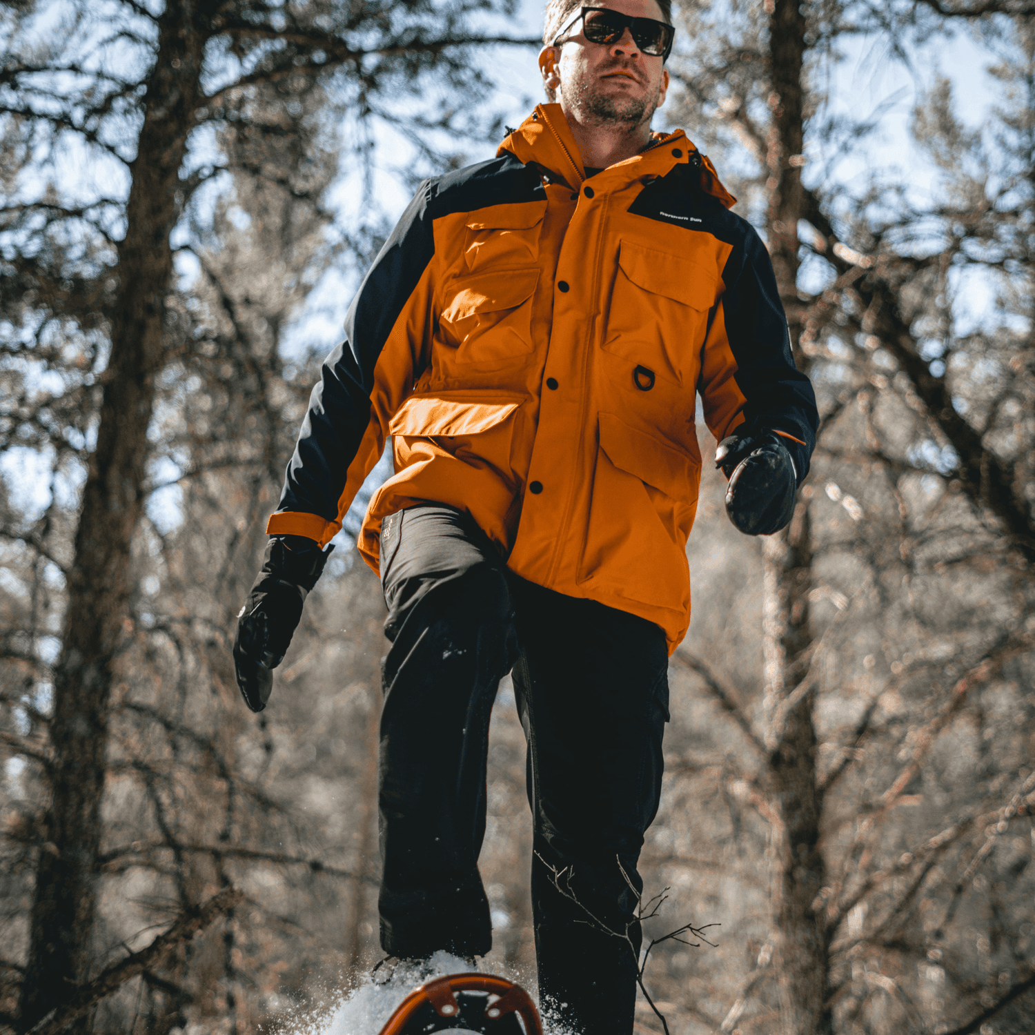 Man snowshoeing in forest wearing Northern Sun 3-in-1 Waterproof Winter Parka, demonstrating mobility and winter performance.