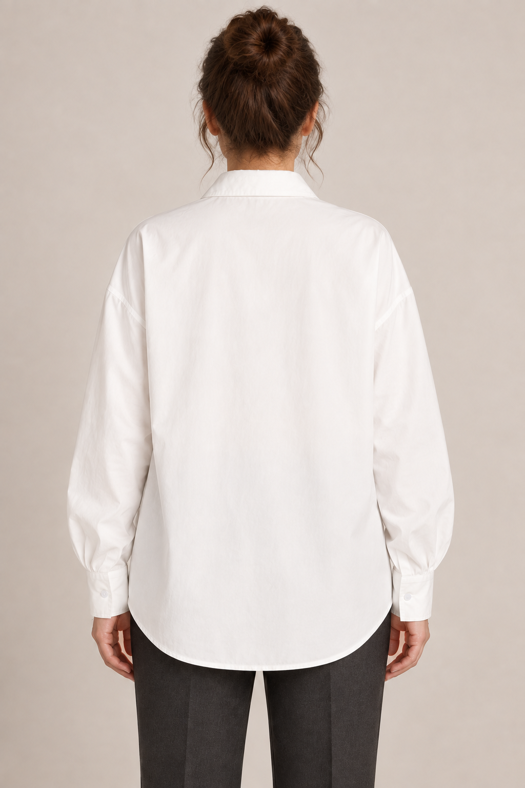 Rear view of the white cotton drop-shoulder shirt with a curved hem on a model.