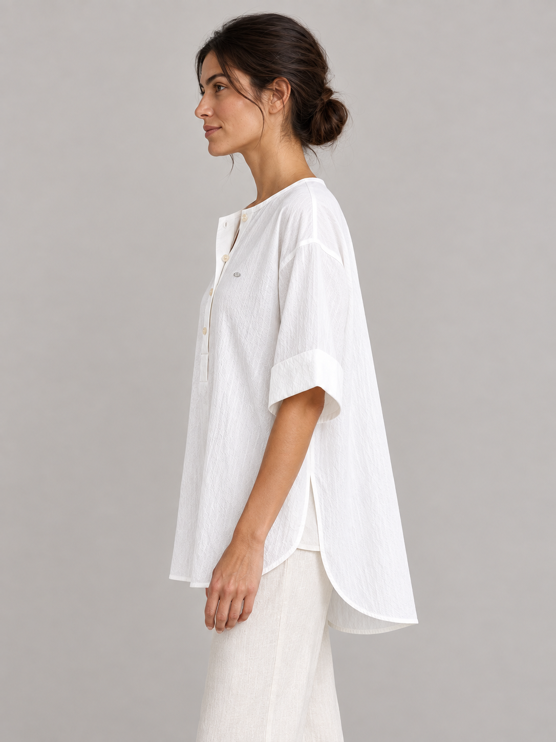 White cotton Henley popover with back pleat, model side.