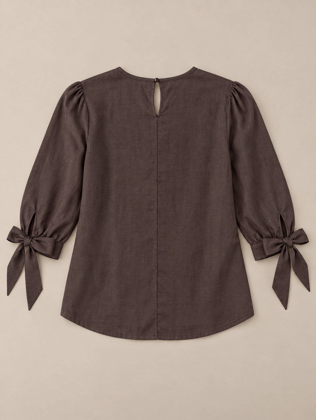 Brown blouse with pleated chest and three-quarter tie cuffs, flat lay back.