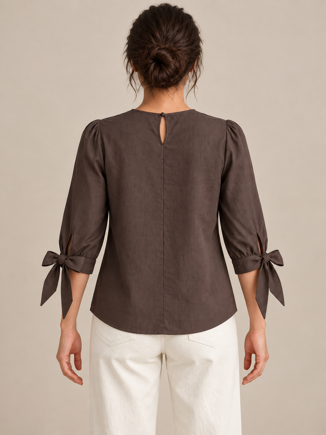 Brown blouse with pleated chest and three-quarter tie cuffs, model back.