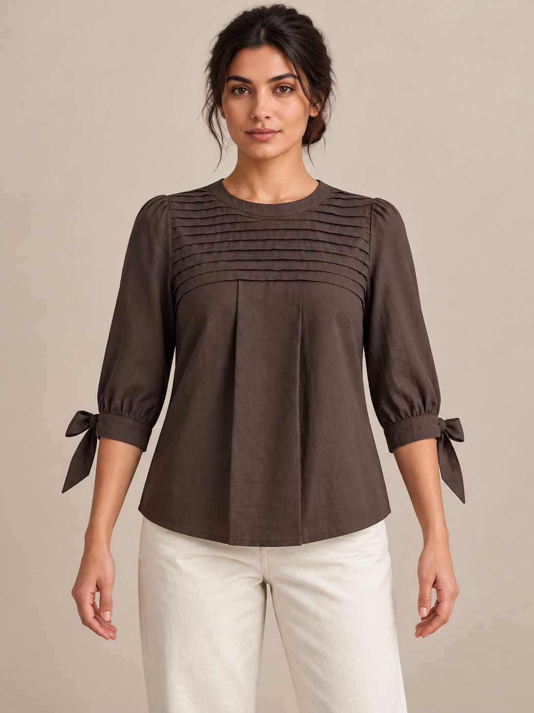 Brown blouse with pleated chest and three-quarter tie cuffs, model front.