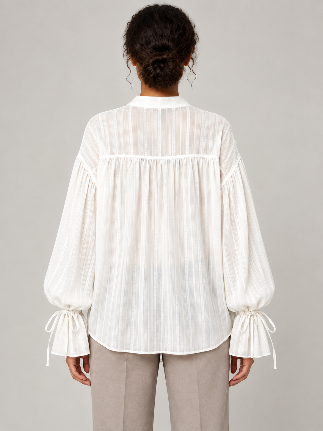 White textured tie-neck blouse with gathered tie cuffs, model back.